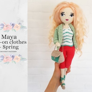 May include: Crochet doll pattern for a spring outfit. The doll is wearing a green cardigan, a striped shirt, red pants, and sandals. She is carrying a small green and brown purse.