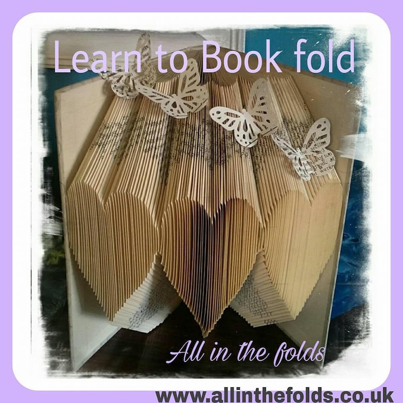 May include: A book folded into a heart shape with paper butterflies on top. The book is titled "Learn to Book fold" and the website "www.allinthefolds.co.uk" is displayed below the heart.