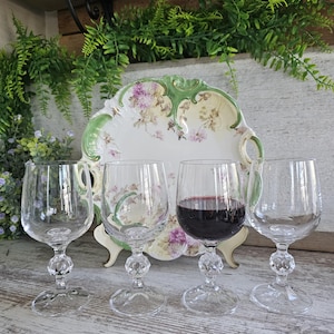 May include: A white ceramic mug with a black handle and the text "But first, coffee" in a black, handwritten-style font. The mug is on a white surface.