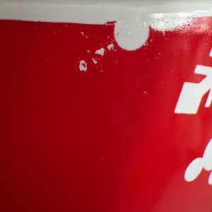 K&ouml;nnte beinhalten: Eine rote Keramiktasse mit wei&szlig;en Maldetails. Die Tasse hat einen Abplatzer am Rand.