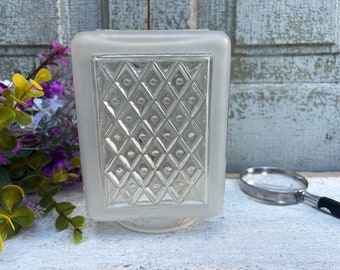 May include: A frosted glass light fixture with a diamond pattern and silver accents. The fixture has a square base and a rectangular shape.