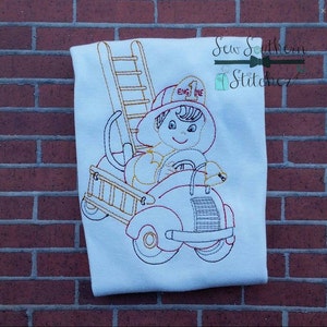Può includere: Design ricamato su tessuto bianco raffigurante un pompiere dei cartoni animati alla guida di un'autopompa. Il pompiere indossa un casco con la scritta "ENGINE 1". Una scala è attaccata al camion. Il disegno è delineato in filo rosso e oro.