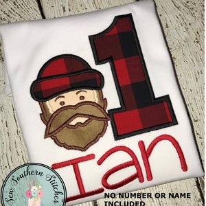 May include: White onesie with a red and black plaid number one and a cartoon lumberjack with a brown beard. The name "Ian" is embroidered in red below the number. The text "No number or name included" is printed below the name.