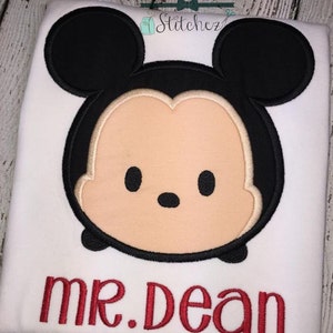 May include: White t-shirt with an embroidered cartoon image of Mickey Mouse with the text "mr. dean" underneath.