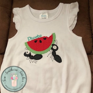 May include: White sleeveless onesie with a watermelon and two ants embroidered on the front. The watermelon is red and green with black seeds. The ants are black. The onesie has a ruffle on the sleeves. The text "Phoebe" is embroidered above the watermelon. The text "Sew Southern Stitches" is embroidered on the bottom of the onesie.