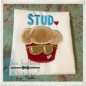 May include: White t-shirt with the text "STUD" in blue with a red heart.  A red cupcake with a brown frosting and gold sunglasses is embroidered on the shirt.  The text "Sew Southern Stitchez" is embroidered below the cupcake.