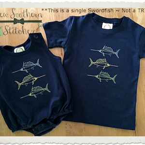 May include: A navy blue baby onesie and t-shirt with a single embroidered swordfish design. The text "This is a single Swordfish ~ Not a TRIO" is visible above the onesie.