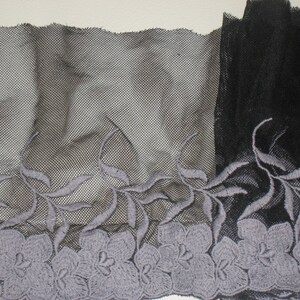 Könnte beinhalten: Schwarzes Netzgewebe mit einem grauen floralen Stickmuster. Die Stickerei zeigt Blätter und Blumen.