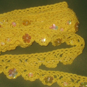 Puede incluir: Borde de crochet amarillo con lentejuelas iridiscentes. El borde tiene un borde festoneado y es perfecto para agregar un toque de elegancia a cualquier proyecto.