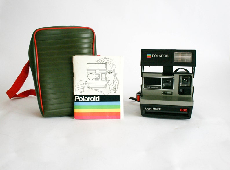 May include: A green and red camera bag with a red strap, a Polaroid 630 Lightmixer camera, and a Polaroid instruction booklet.