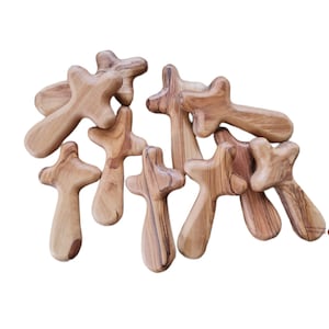 Puede incluir: Un grupo de pequeñas cruces de madera hechas de madera de olivo. Las cruces son de diferentes tamaños y formas, pero todas están talladas en el mismo estilo. Son una forma hermosa y única de mostrar tu fe.