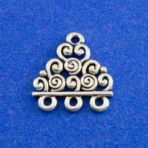May include: Silver-toned metal charm with a decorative design of swirling circles and a straight bar with four loops at the bottom.