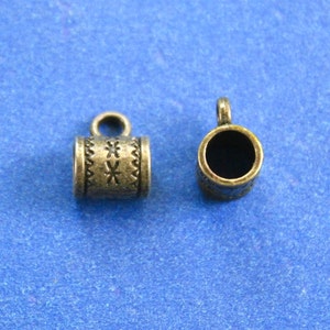 Puede incluir: Dos tapones de cordón de metal plateado antiguo con un diseño decorativo. Los tapones tienen un pequeño bucle en la parte superior para sujetarlos a un cordón.