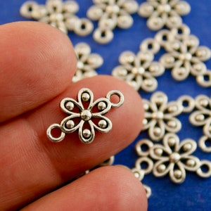 May include: Silver flower charm with a beaded center and two loops for attaching to jewelry or crafts.