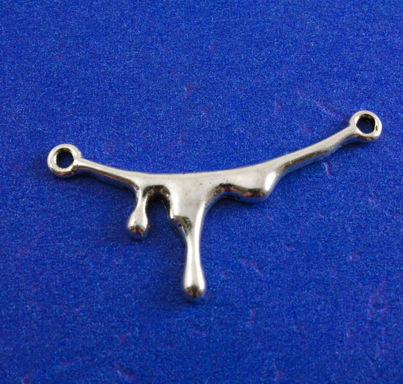 May include: Silver-toned metal charm shaped like a dripping liquid. The charm has two loops for attaching to jewelry or other crafts.