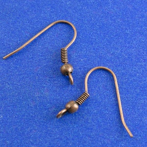 Pode incluir: Dois ganchos para brincos de cobre com fecho de mola e uma pequena bola na ponta.
