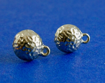 May include: Two silver-colored, textured ball charms with small loops. The charms have a hammered appearance and are set against a blue background. These charms are suitable for jewelry making.