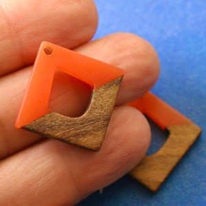 May include: A pair of orange and brown wood earrings with a square shape and a hole at the top for hanging.
