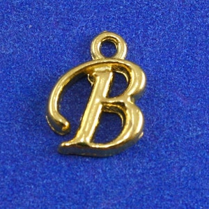 May include: Gold-colored metal charm in the shape of the letter B. The letter is in a cursive font.