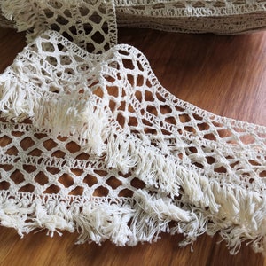 May include: White crocheted trim with a diamond pattern and fringe. The trim is made of cotton and is ideal for adding a touch of elegance to any project.