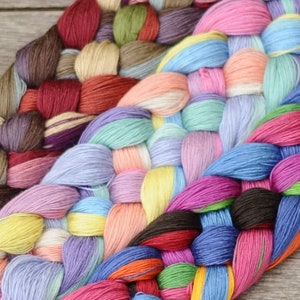 May include: A close-up shot of a woven textile made from colourful yarn bundles. The yarn is arranged in a basket-weave pattern, with shades of pink, blue, yellow, and brown. The texture appears soft, suggesting a handmade craft item.