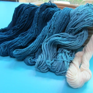 May include: A collection of yarn in shades of blue and white. The yarn is arranged in a basket and is ready for knitting or crocheting.