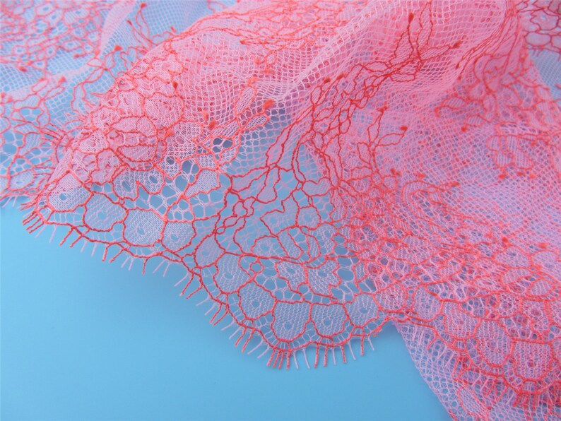 Peut inclure: Tissu de dentelle rose et rouge avec un motif floral d&eacute;licat. La dentelle est douce et transparente, et elle a une surface l&eacute;g&egrave;rement textur&eacute;e.