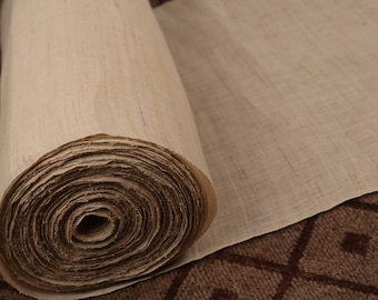 May include: A roll of natural beige fabric, tightly wound and ready to be unrolled. The fabric has a subtle texture and a slightly rough feel.