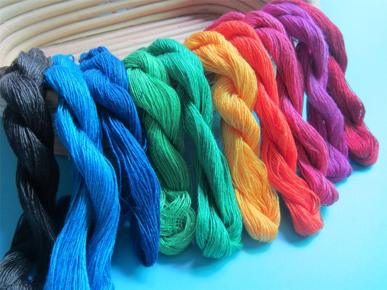 May include: A selection of vibrant embroidery threads in a spectrum of colours, from black to pink. The threads are displayed in a neat arrangement, highlighting their rich hues and textures. Suitable for various craft projects.