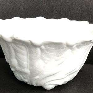 Könnte beinhalten: Weiße Keramikschale mit gewelltem Rand und einem strukturierten, floralen Design. Die Schale hat einen Durchmesser von etwa 15 cm.