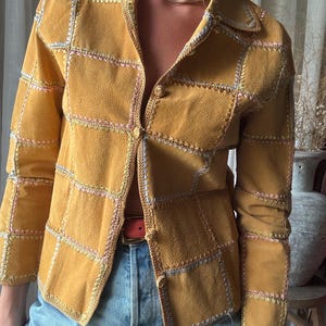 Preciosa chaqueta vintage de ante color mostaza tostado con patchwork y detalles de costuras bordadas en rosa, azul y verde, estilo bohemio, ideal para festivales.