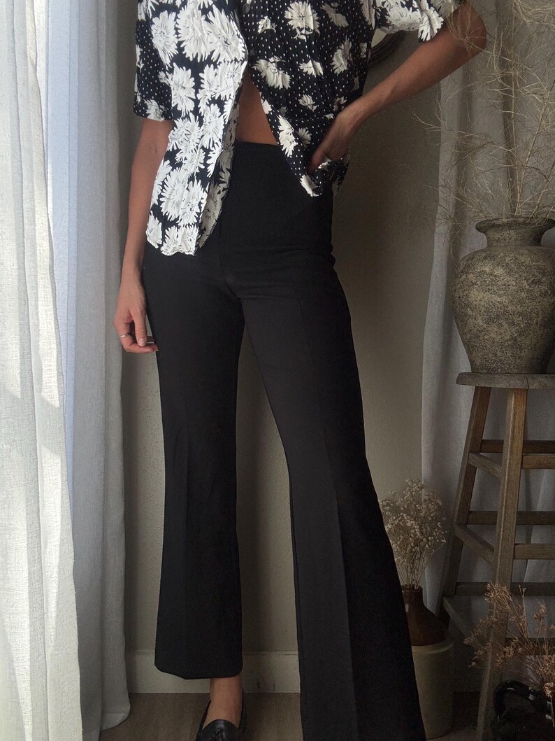 Puede incluir: Pantal&oacute;n negro acampanado de cintura alta. El pantal&oacute;n est&aacute; hecho de una tela suave y el&aacute;stica.