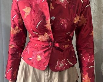 May include: A deep red blazer featuring an all-over floral embroidery pattern in shades of orange and cream. The jacket has long sleeves, a notched collar, a single button closure, and a matching fabric belt with a rectangular metal buckle.