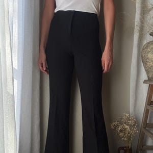 Puede incluir: Pantal&oacute;n negro acampanado de cintura alta y pierna recta.