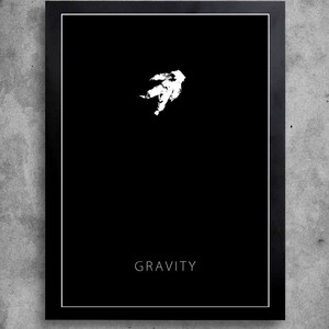 Op de afbeelding: Een minimalistische zwart-wit poster met een wit silhouet van een astronaut die in de ruimte zweeft. De tekst "GRAVITY" is in wit onderaan de poster gedrukt.