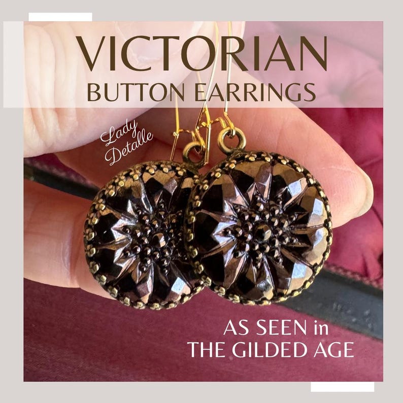 K&ouml;nnte beinhalten: Viktorianische Knopf-Ohrringe in dunkelbrauner Farbe mit goldenen Akzenten. Die Ohrringe werden in einer Hand gezeigt, wobei der Text "Lady Detalle" und "AS SEEN in THE GILDED AGE" auf dem Bild sichtbar ist.