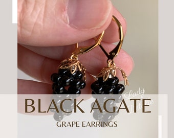 May include: Black agate grape earrings with gold-toned hoops and a delicate floral design.  The earrings are made with black agate beads and are a beautiful and unique piece of jewelry.