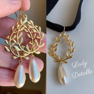 May include: Gold leaf earrings with a pearl drop and a matching gold leaf necklace with a pearl drop. The necklace is on a black ribbon.