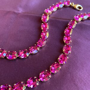 May include: A pink crystal necklace with oval-shaped stones set in gold.