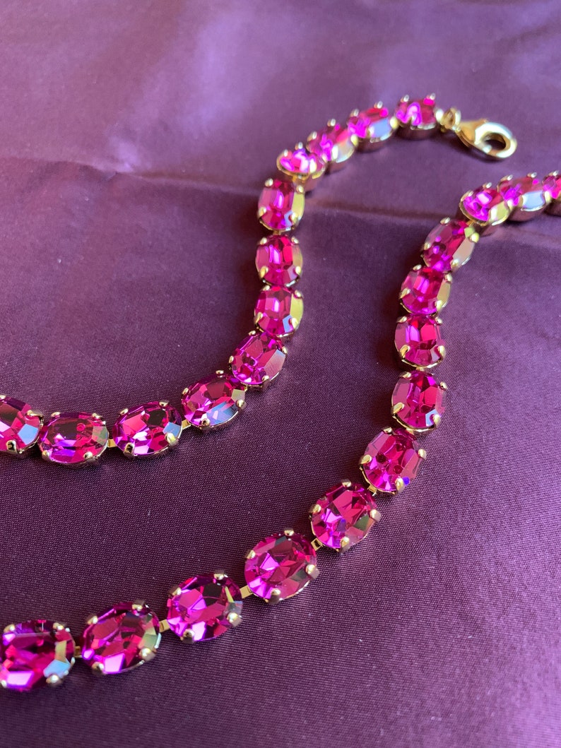May include: A pink crystal necklace with oval-shaped stones set in gold.