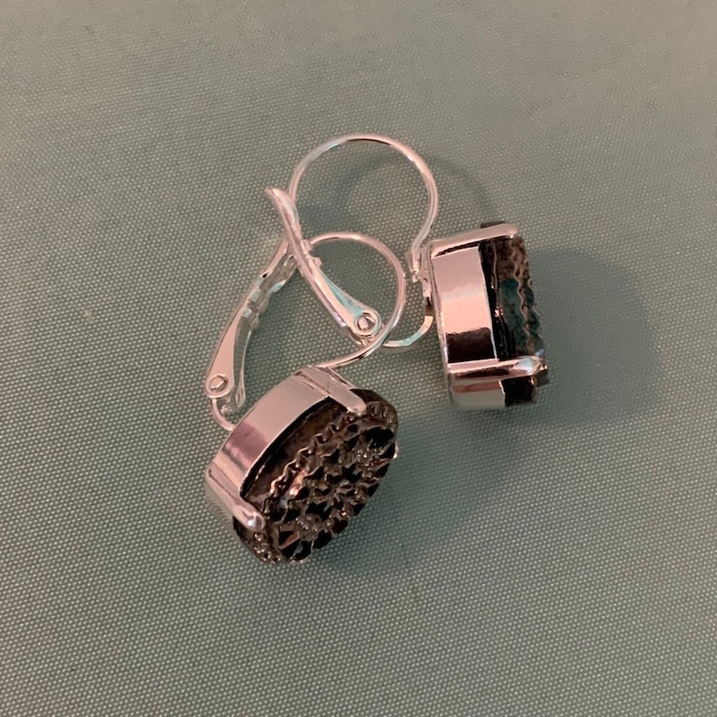 May include: A pair of silver clip-on earrings with black gemstone accents. The earrings have a simple, elegant design.