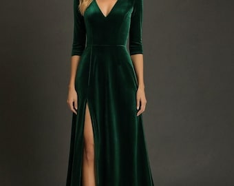 May include: A long, emerald green velvet gown with a V-neckline and three-quarter sleeves. The dress features a high slit on the left side, showcasing the leg. The elegant design is suitable for formal events.
