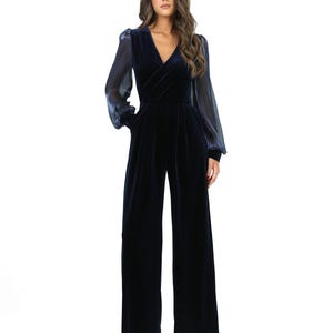 May include: A navy blue velvet jumpsuit with a V-neck and wide-leg trousers. The long sleeves are sheer. This elegant jumpsuit has a tailored fit and is suitable for formal occasions. The measurements are in centimetres.