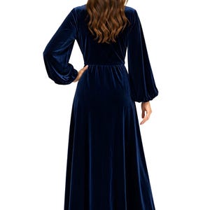 Navy blue velvet maxi dress with long loose sleeves. The dress features a fitted bodice and a flowing a line skirt.