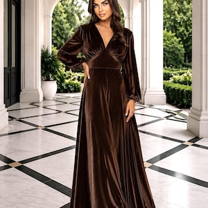 Brown velvet maxi dress with a V-neck and long sleeves. The dress features a fitted bodice and a flowing skirt.