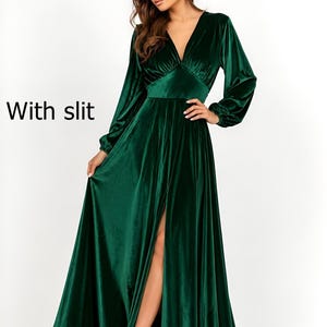 A long, emerald green velvet dress with a deep V-neck and long sleeves. The dress features a high slit on the left leg and a fitted waist. The text "With slit" is visible on the left side of the image.