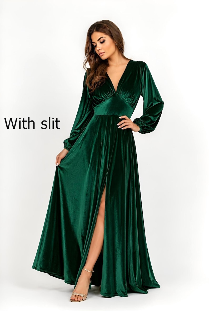 A long, emerald green velvet dress with a deep V-neck and long sleeves. The dress features a high slit on the left leg and a fitted waist. The text "With slit" is visible on the left side of the image.