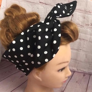 May include: A black fabric headband with white polka dots, styled with a bow. The headband is displayed on a mannequin head with auburn hair. The polka dots are evenly spaced across the black material.