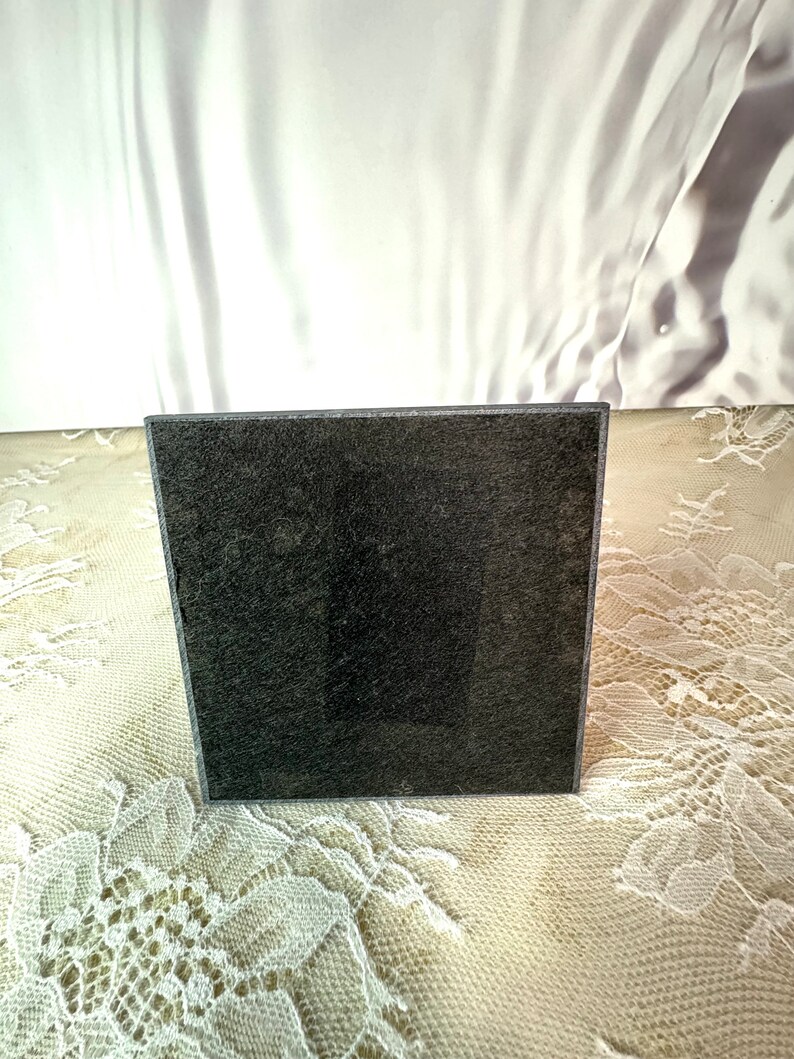 May include: A black square coaster with a textured surface.
