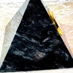 May include: A black marble pyramid with a gold-colored clock face on one side.